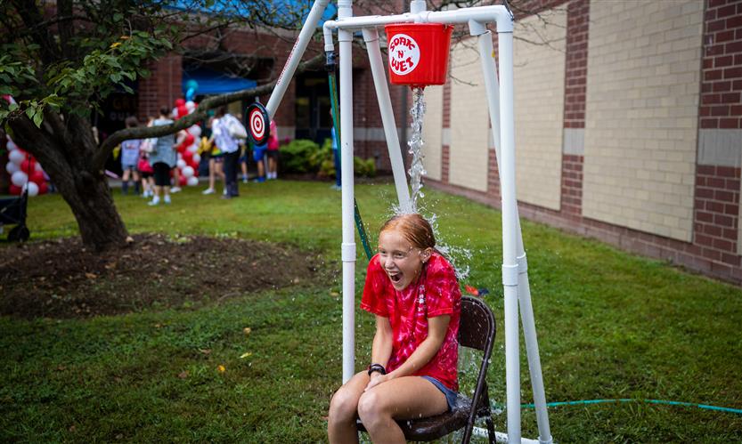 A girl gets water poured on her at a dunking booth